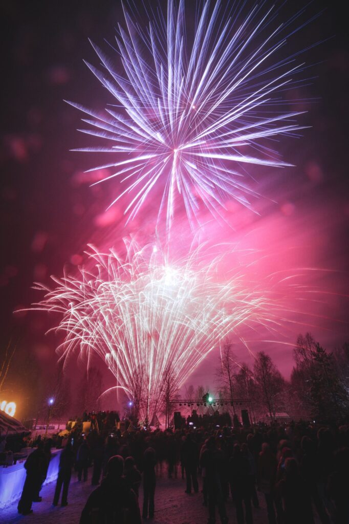 Ilotulitus lumisten puiden yllä Rovaniemellä uutena vuotena