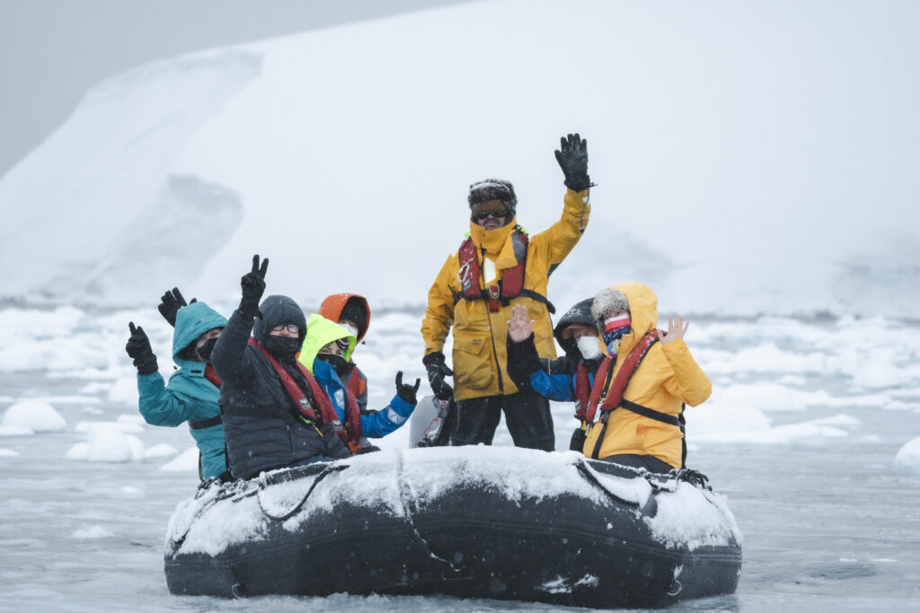 Expedition guests in a Zodiac amid Antarctic ice and snowfall