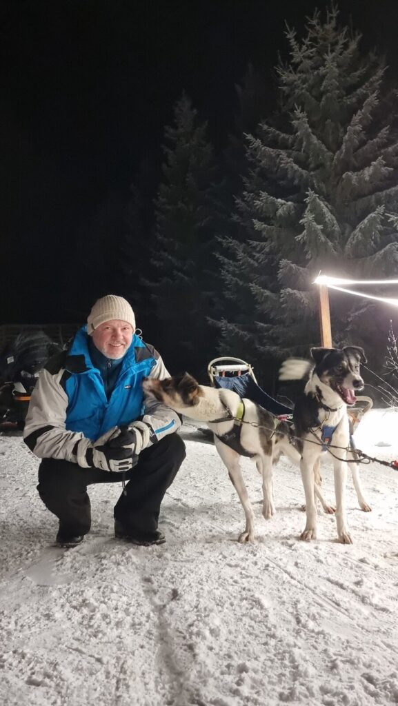 Viajero con huskies antes de un paseo nocturno en trineo en Vuokatti