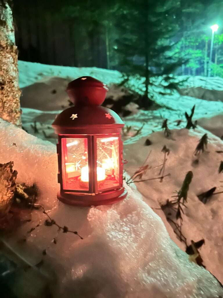 Farol cálido junto a un sendero nevado del bosque de Vuokatti