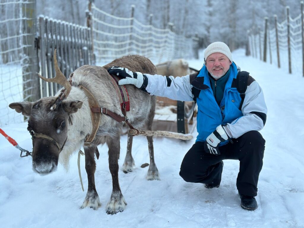 Viajero con un reno en una granja nevada de Vuokatti