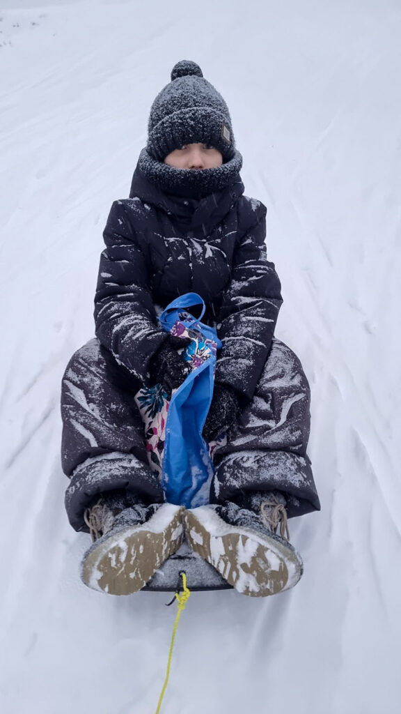 Child on a sled during a snowy family activity in Vuokatti